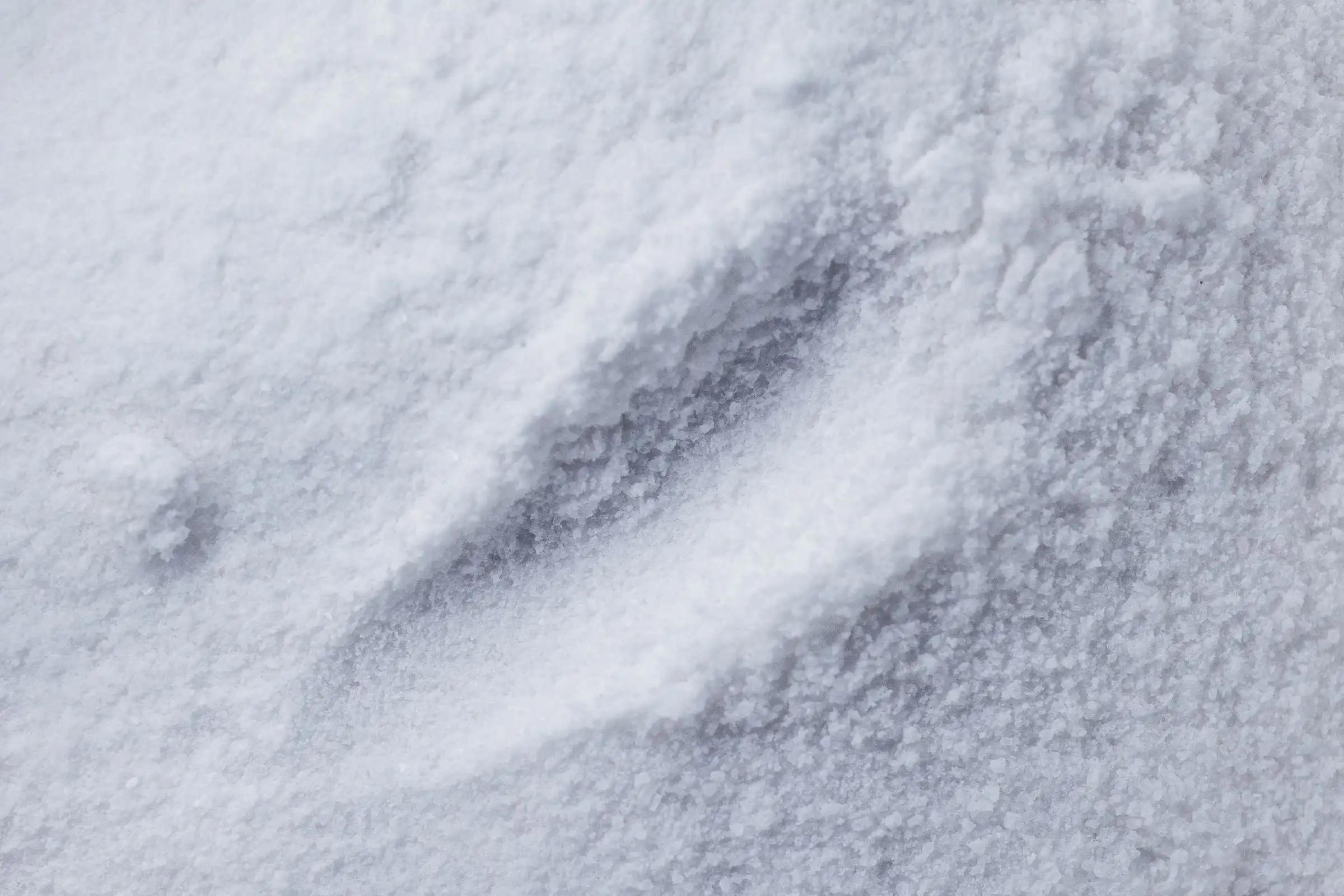 Macro view of fine white polymer powder, drifted into soft ridges