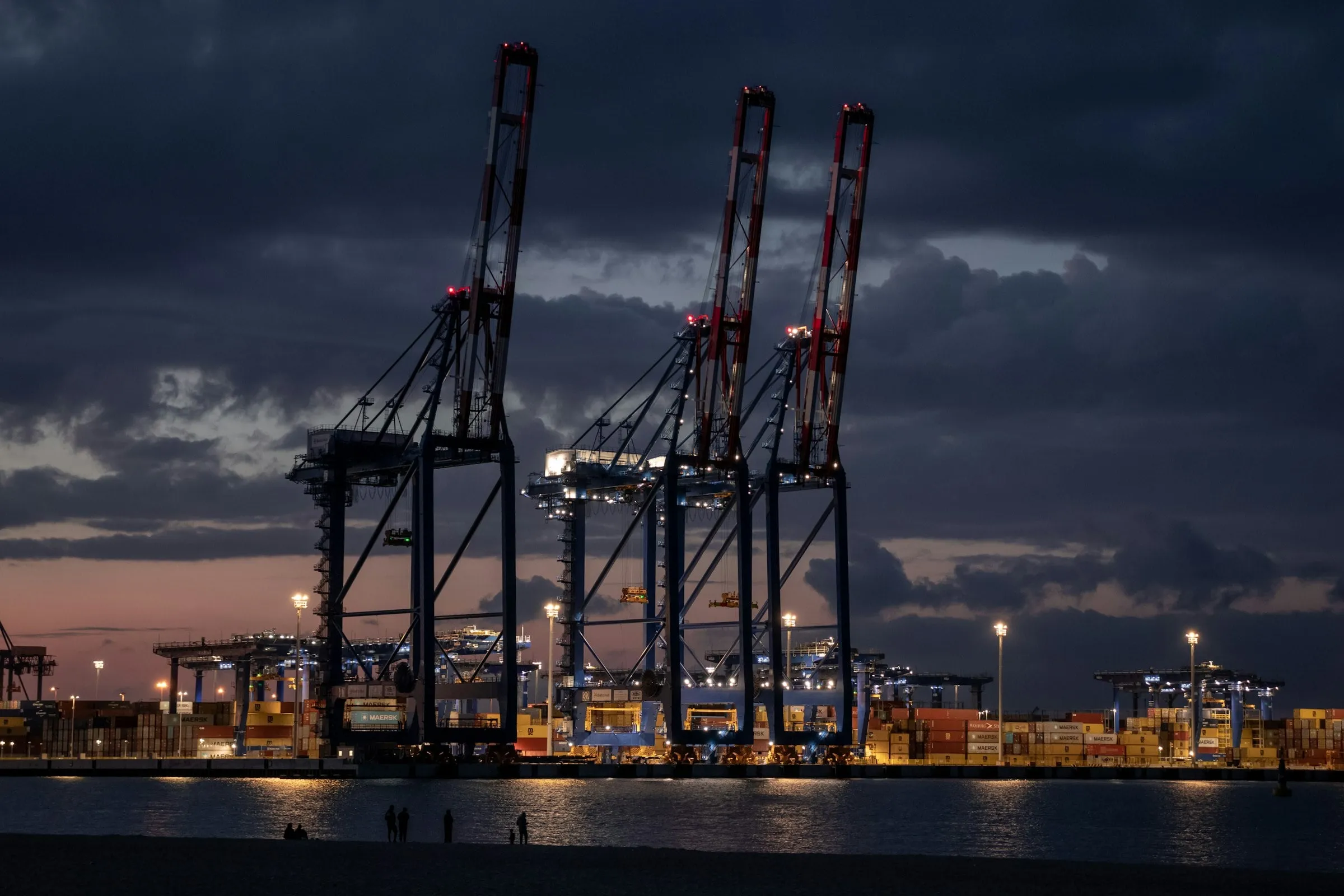 Container gantry cranes silhouetted against a dusk sky