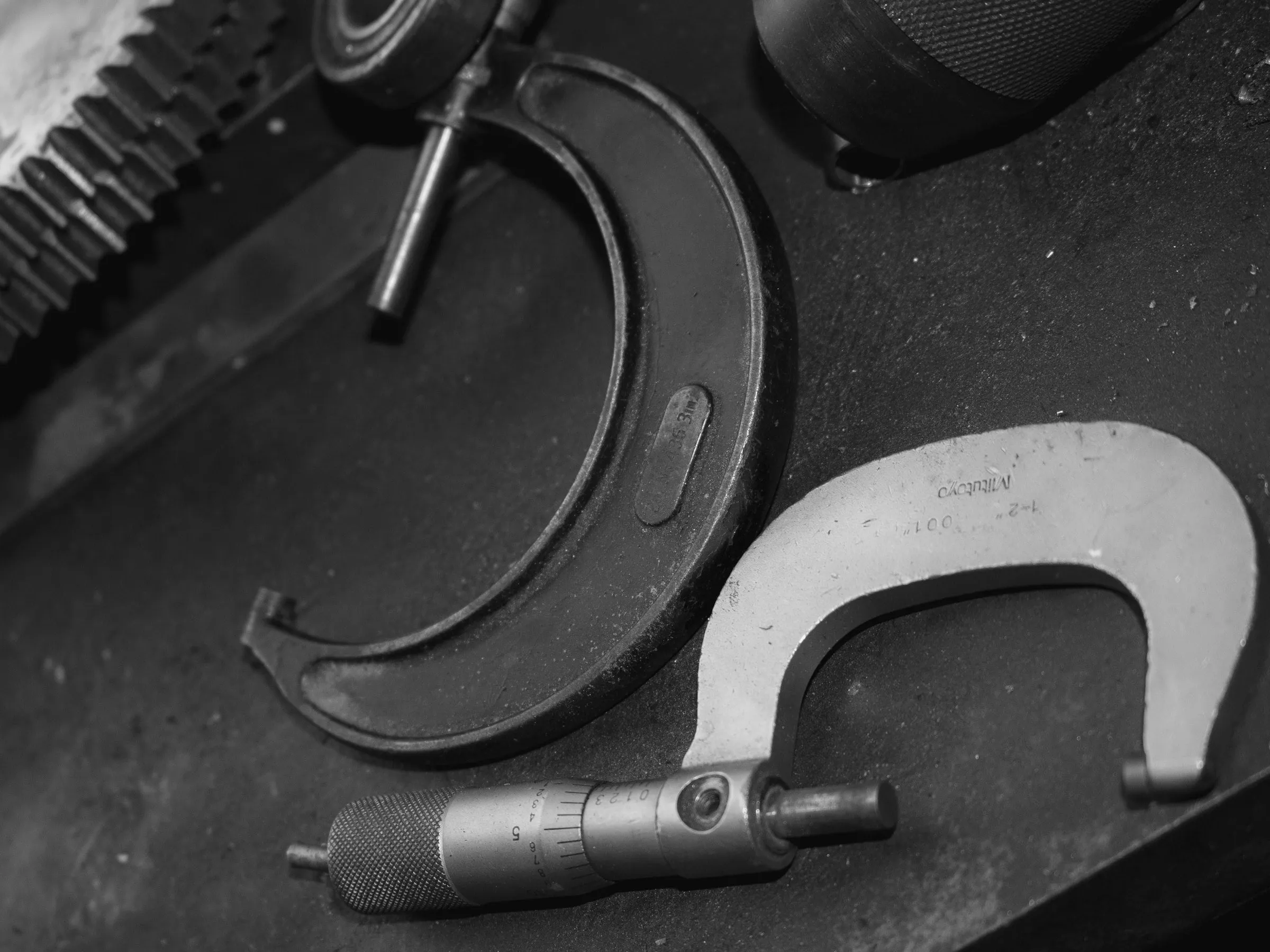 Micrometer and vernier caliper on a dark surface